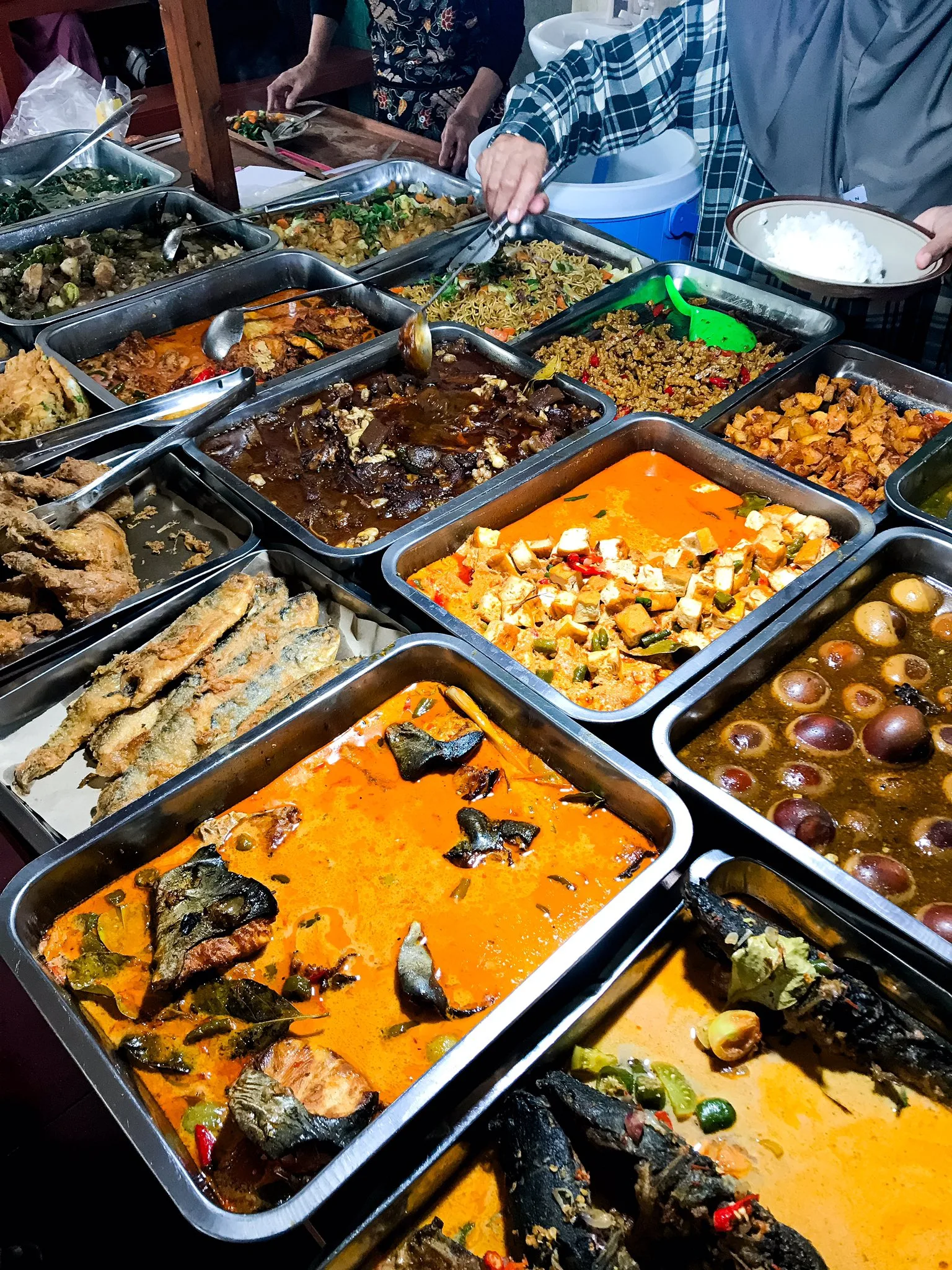 Customers choosing their own dishes in front of a warung counter