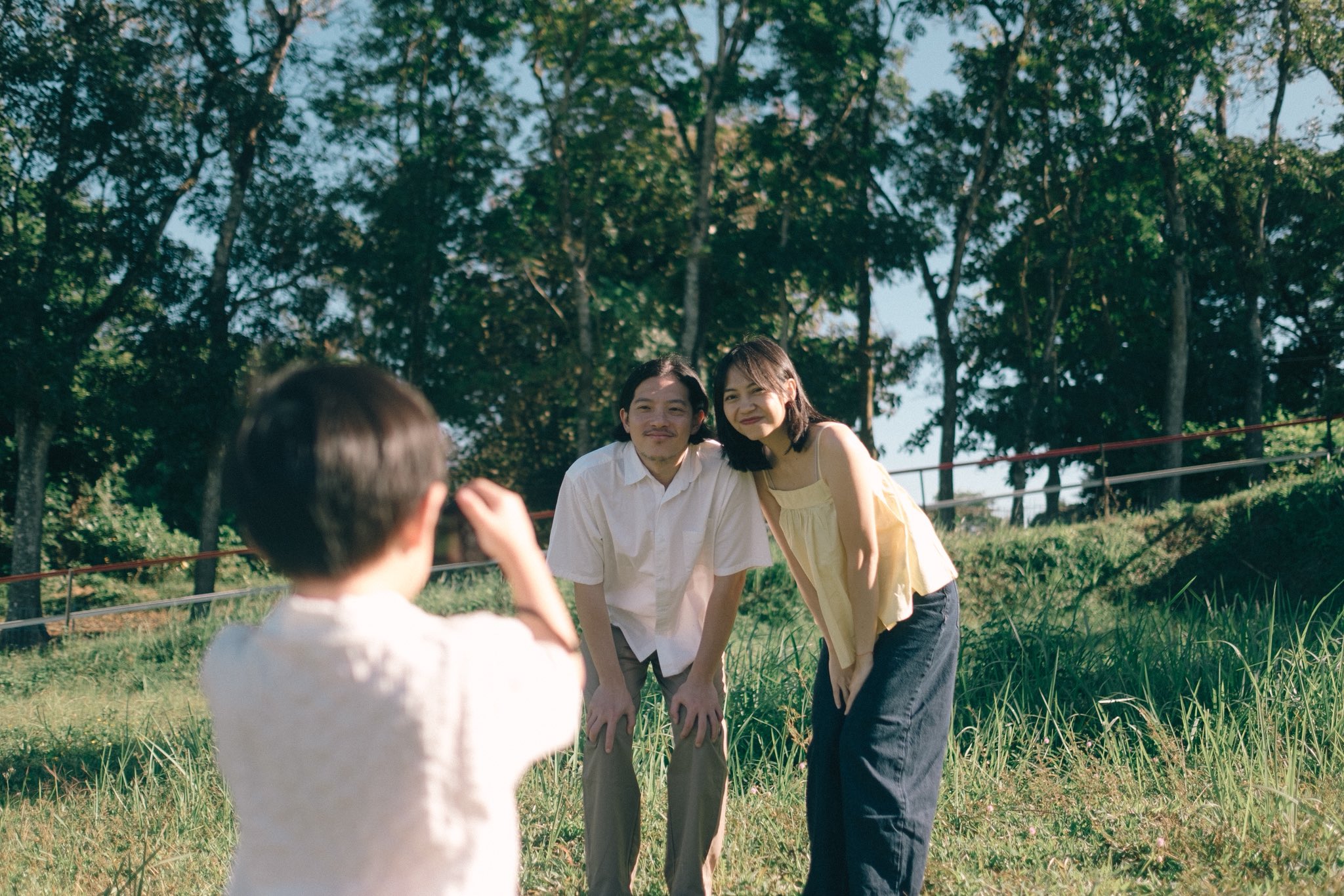 A child photographing their parents in the grassland