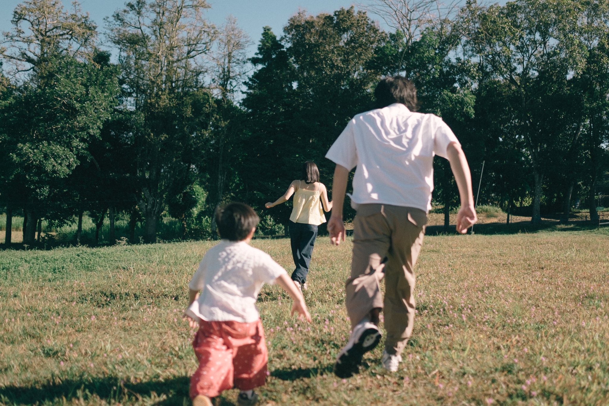 A family running together across the open grass